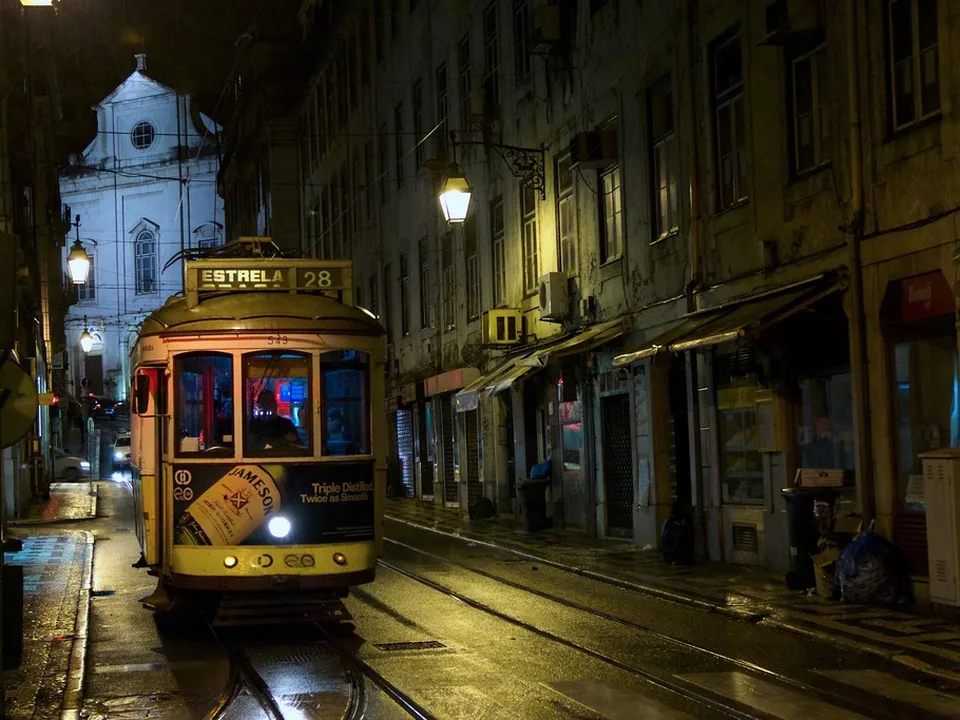 A yellow tram on a Lisbon street at night